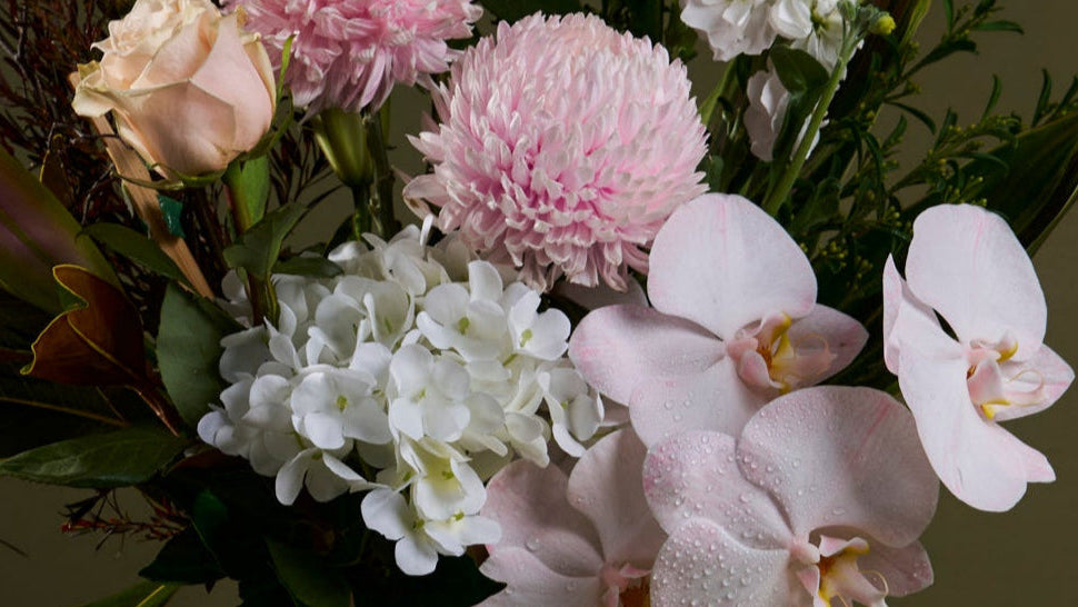 Bouquet of pink and white flowers with green leaves on a dark background